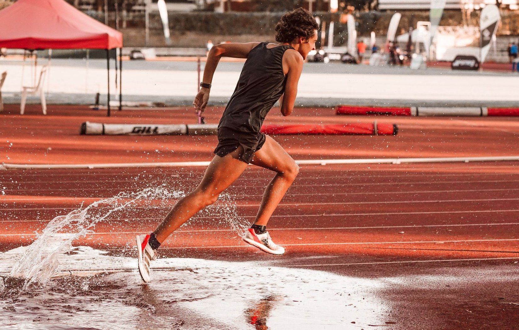 A track athlete in full stride, splashing through water