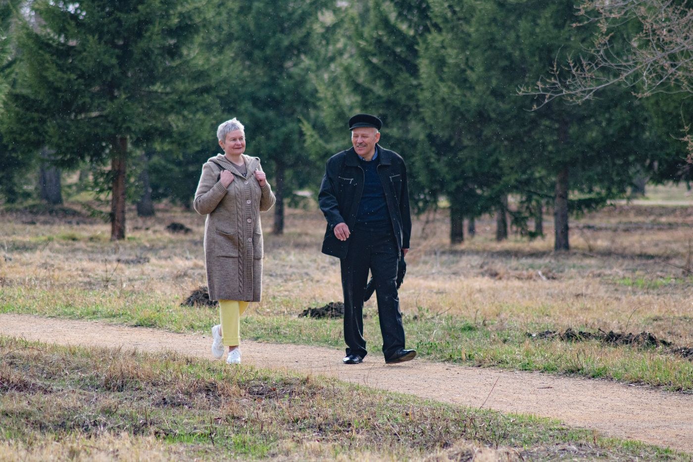 Two older adults walking along a path