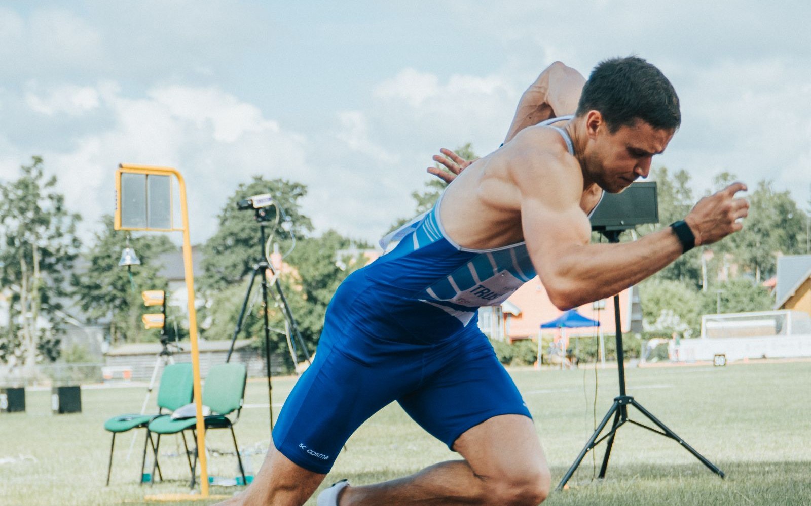 A sprinter driving out of the starting blocks in front of a track camera